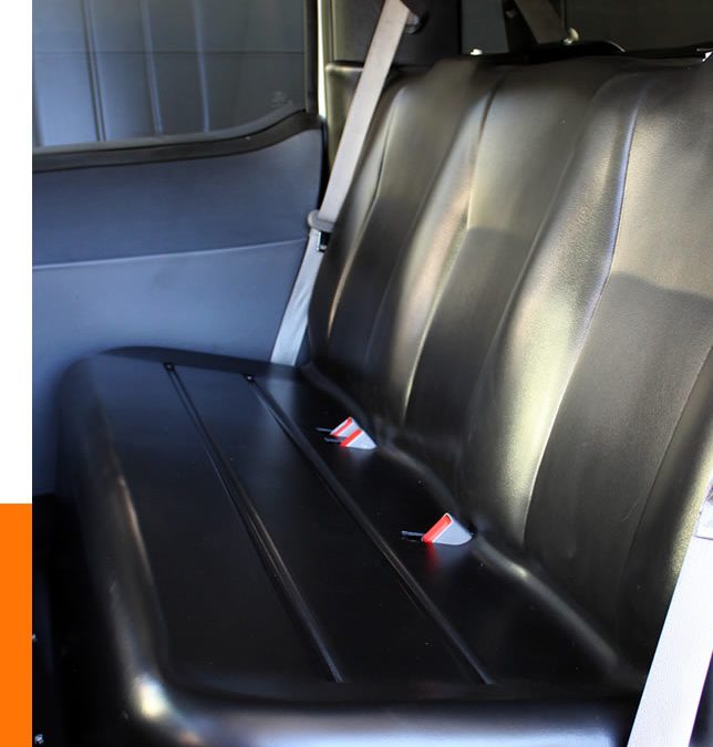 Custom automotive product fabrication shines through in this black leather car bench seat, complete with seatbelts, perfectly integrated into the vehicle interior.